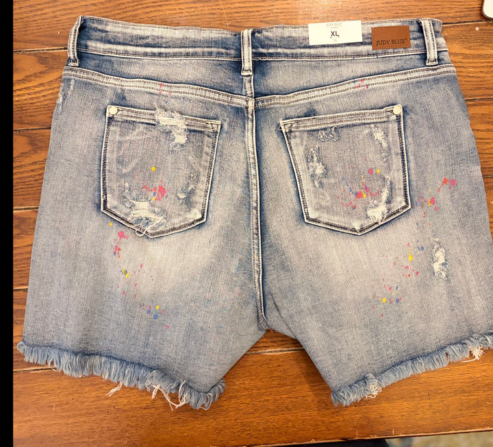 Judy Blue- Mid-Rise Rainbow Paint Splash Cutoff Shorts.
