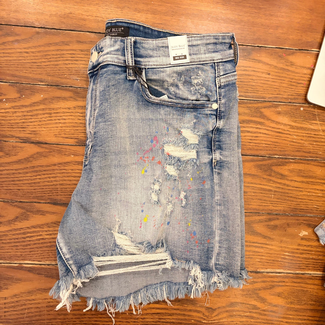 Judy Blue- Mid-Rise Rainbow Paint Splash Cutoff Shorts.